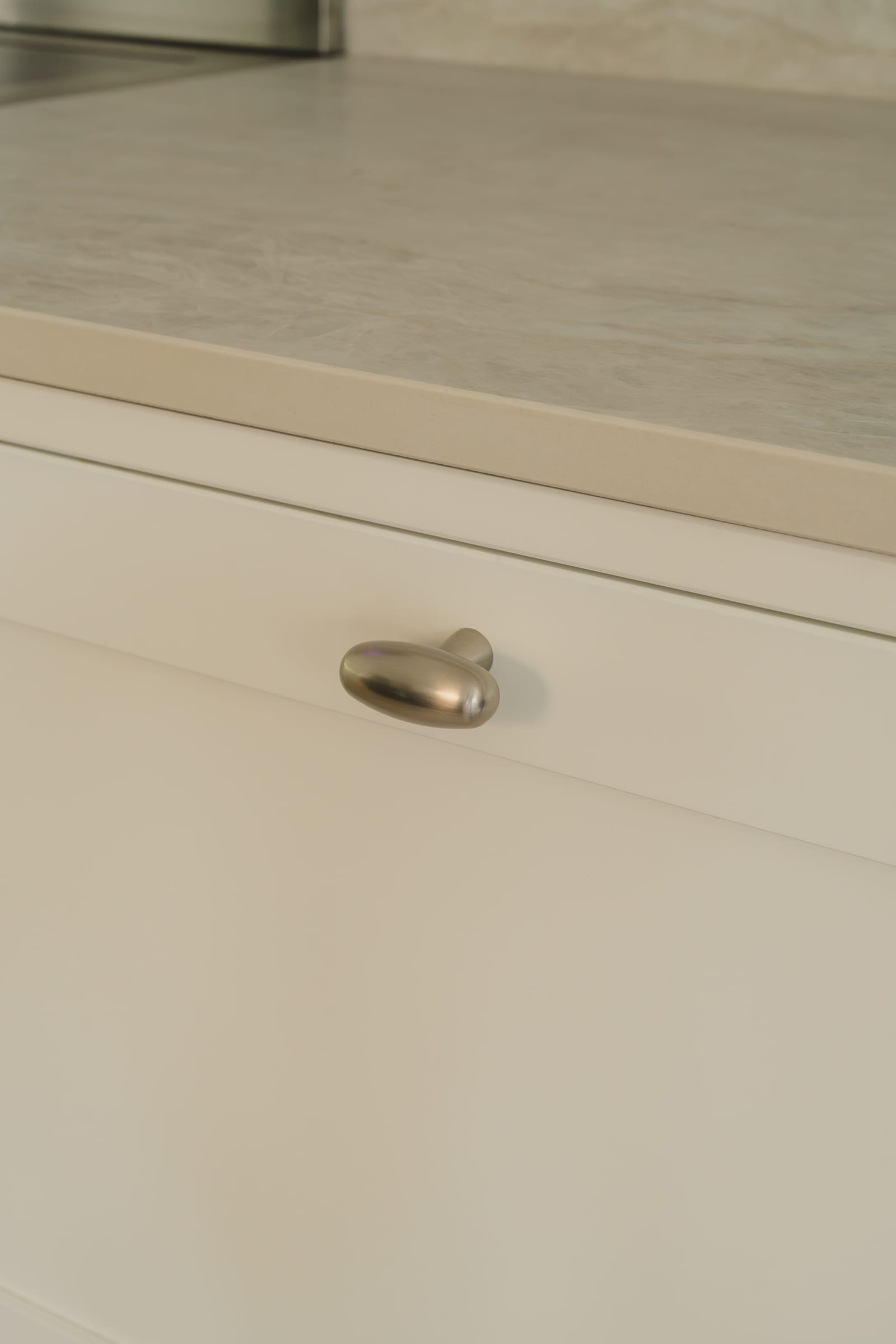 Knopp på en ljus ramlucka under bänkskivan i Dekton Nara