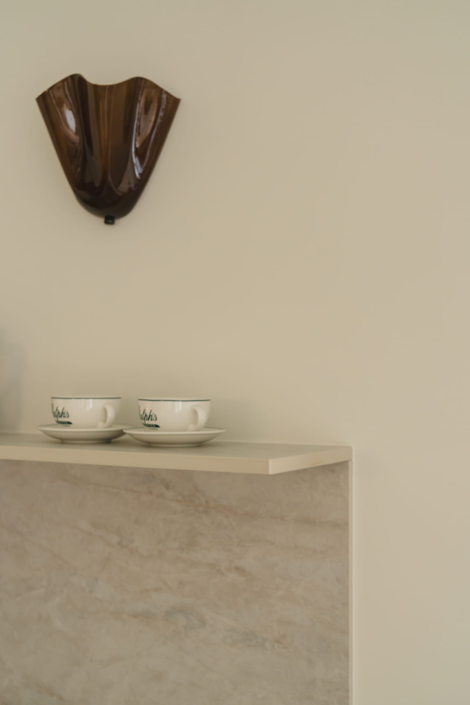 Hylla i Dekton Nara med två kaffekoppar, under en vägglampa